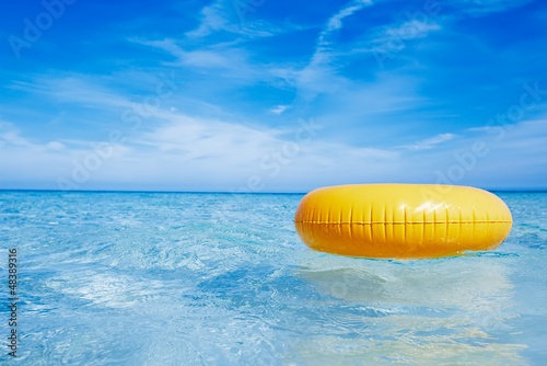 Photo: floating yellow ring on crystal blue sea water with sky, shallow floating yellow ring on crystal blue sea water with sky, shallow