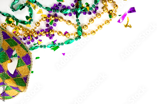 Photo: A Mardi gras mask and beads on a white background with copy spac A Mardi gras mask and beads on a white background with copy spac