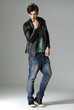 serious young man in leather jacket on gray background