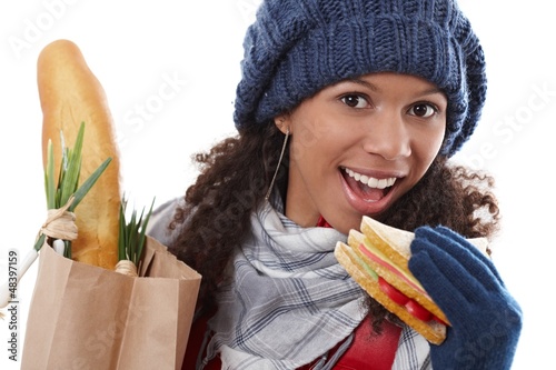 Photo: Attractive female biting sandwich at wintertime Attractive female biting sandwich at wintertime
