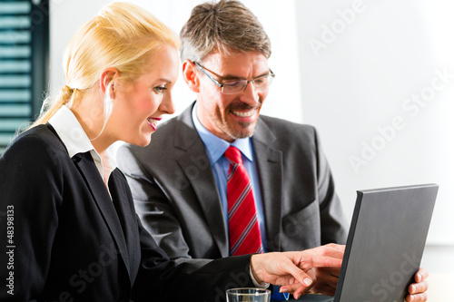 Photo: Businesspeople looking at laptop in consultation Businesspeople looking at laptop in consultation