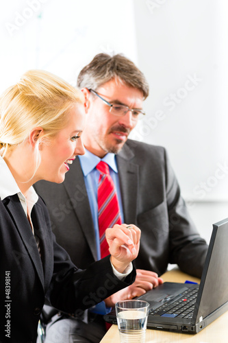 Photo: Businesspeople looking at laptop in consultation Businesspeople looking at laptop in consultation