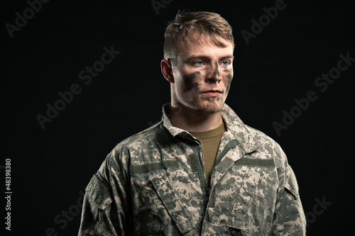 Photo: Military young man with camouflage on face. Studio shot. Military young man with camouflage on face. Studio shot.