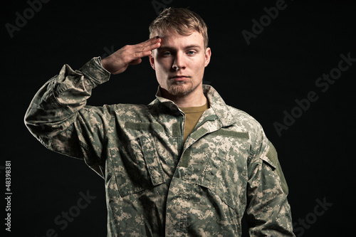 Photo: Military young man salutes. Studio portrait. Military young man salutes. Studio portrait.