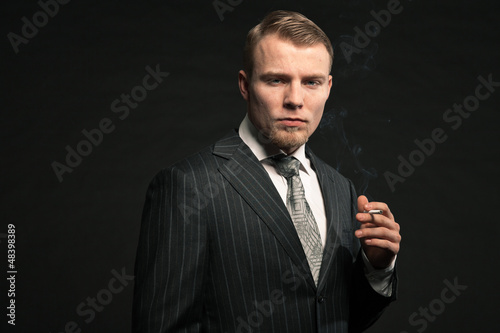 Photo: Fashion man in suit smoking cigarette. Studio shot. Fashion man in suit smoking cigarette. Studio shot.