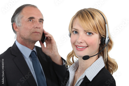 Photo: Woman in a headset next to a man with a cellphone Woman in a headset next to a man with a cellphone