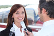 Reporter interviewing woman in airport