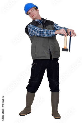 Photo: craftsman holding a hammer and a wedge and looking disgusted craftsman holding a hammer and a wedge and looking disgusted