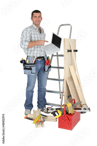 Photo: Carpenter stood by ladder with laptop Carpenter stood by ladder with laptop