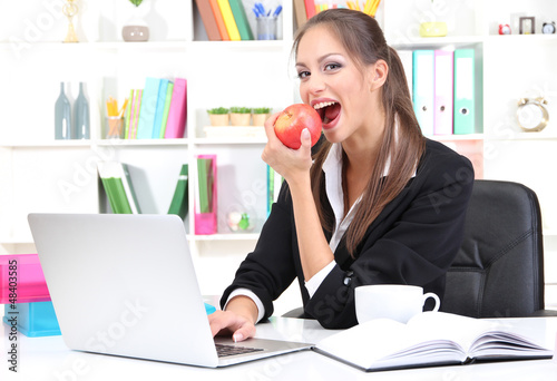 Photo: Young businesswoman eating an apple Young businesswoman eating an apple