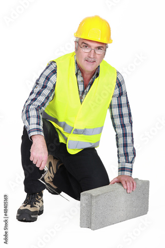 Photo: mature bricklayer with concrete block and trowel mature bricklayer with concrete block and trowel