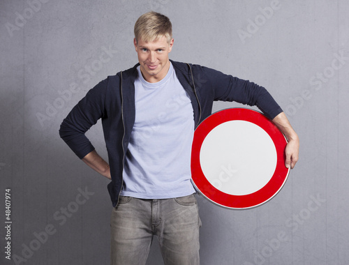Photo: Smiling man holding universal forbidden sign. Smiling man holding universal forbidden sign.
