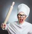 Photo: Angry woman cook trying to hit with a rolling pin over a gray Angry woman cook trying to hit with a rolling pin over a gray