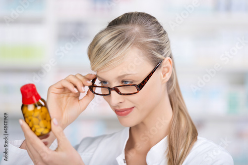 Photo: apothekerin schaut prüfend auf medikament apothekerin schaut prüfend auf medikament