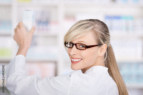 Photo: apothekerin nimmt ein medikament aus dem regal apothekerin nimmt ein medikament aus dem regal