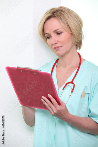 Photo: A female doctor taking notes on a clipboard. A female doctor taking notes on a clipboard.