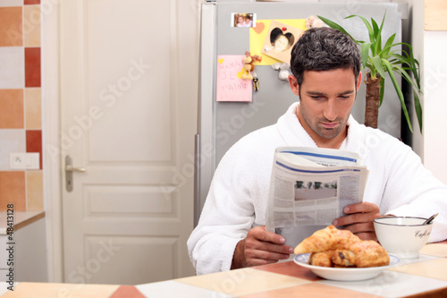 Photo: Man reading his newspaper over breakfast Man reading his newspaper over breakfast