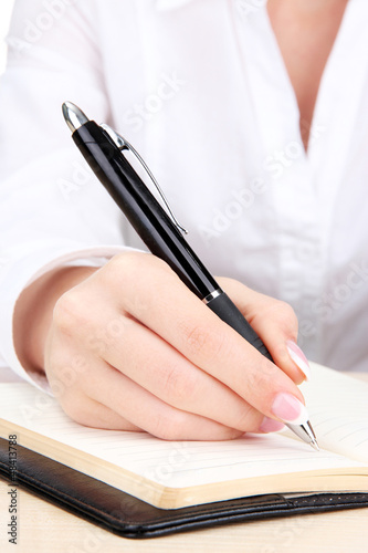 Photo: Closeup of businesswoman hand, writing on paper Closeup of businesswoman hand, writing on paper