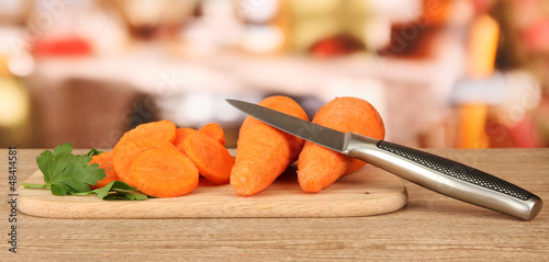 Photo: carrots with knife on cutting board on table in kitchen carrots with knife on cutting board on table in kitchen