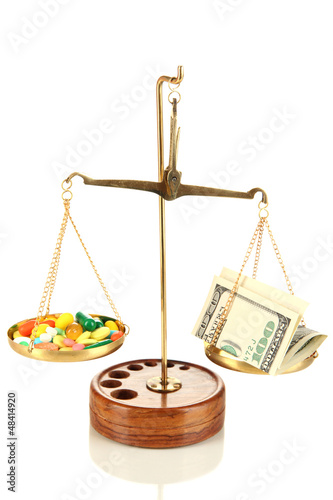 Photo: Pills and money in scales isolated on white Pills and money in scales isolated on white