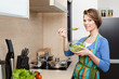 Pretty woman in striped apron chops vegetables 