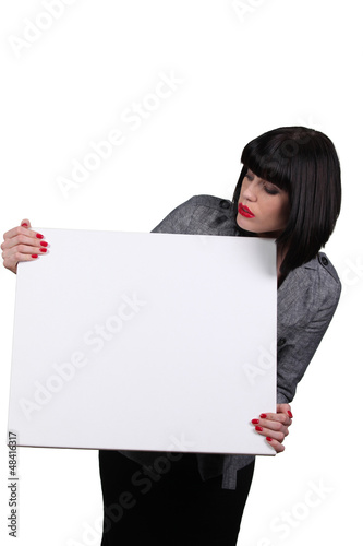 Photo: Young woman holding white panel Young woman holding white panel