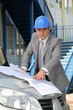 Architect looking at plans on a car bonnet
