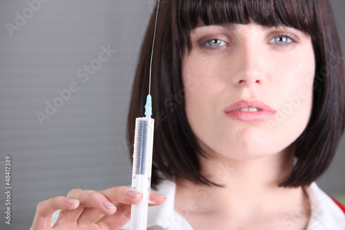 Photo: Serious female doctor holding a syringe Serious female doctor holding a syringe