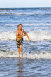 young boy running through the water at the beach