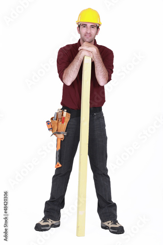 Photo: Carpenter stood with plank of wood Carpenter stood with plank of wood