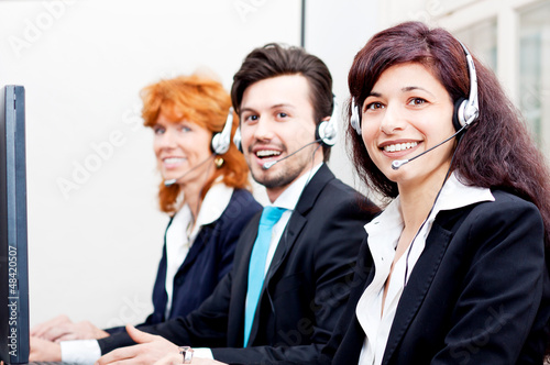 Photo: Callcenter Mitarbeiter mit Kopfhörern am Computer freundlich Callcenter Mitarbeiter mit Kopfhörern am Computer freundlich