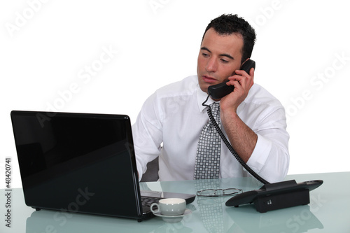 Photo: businessman talking on the phone in his office businessman talking on the phone in his office