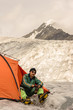 The rock-climber in tent looks to tops mountains