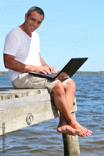 Photo: man with a laptop on holidays man with a laptop on holidays