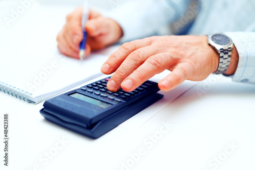Photo: Closeup of a businessman calculating Closeup of a businessman calculating