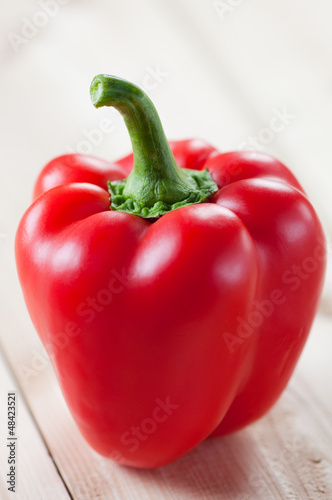 Photo: Close-up of a red bell pepper on wooden boards, studio shot Close-up of a red bell pepper on wooden boards, studio shot