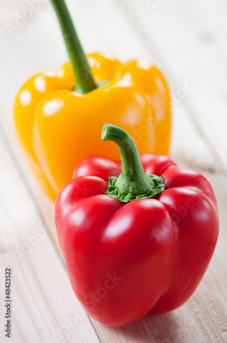 Photo: Red and yellow bell peppers on wooden boards, vertical shot Red and yellow bell peppers on wooden boards, vertical shot