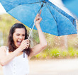 playful young woman holding umbrella in the rain