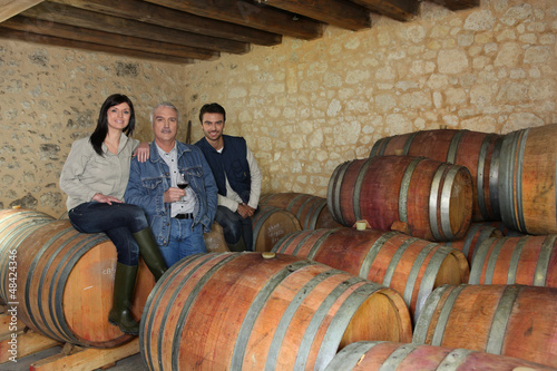 Photo: three people drinking wine in a cellar three people drinking wine in a cellar