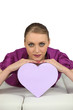 Young woman lying with heart-shaped box