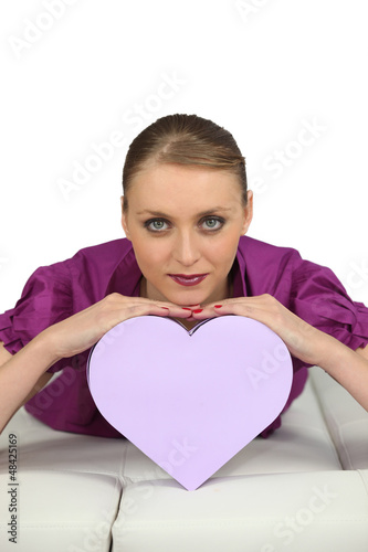 Photo: Young woman lying with heart-shaped box Young woman lying with heart-shaped box