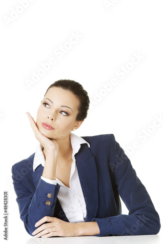 Photo: Pretty young woman sitting at the desk and thinking Pretty young woman sitting at the desk and thinking