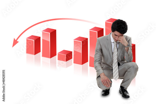 Photo: Depressed businessman in front of a bar chart Depressed businessman in front of a bar chart