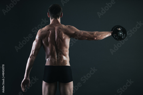 Photo: Back of young male bodybuilder doing weight exercise Back of young male bodybuilder doing weight exercise