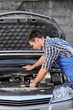 Young mechanic in overalls examining an automobile