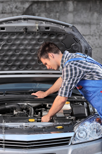 Photo: Young mechanic in overalls examining an automobile Young mechanic in overalls examining an automobile