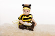 Baby wearing bee costume sitting on the floor