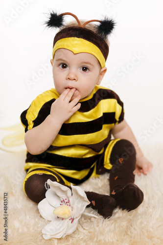Photo: Baby wearing bee costume sitting on the floor Baby wearing bee costume sitting on the floor