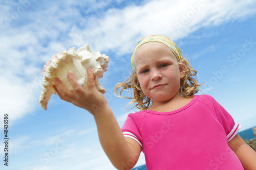 Photo: cute smiling child girl with big sea shell cute smiling child girl with big sea shell