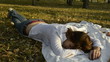 Young woman sleeping on a bedspread in the park and the autumn